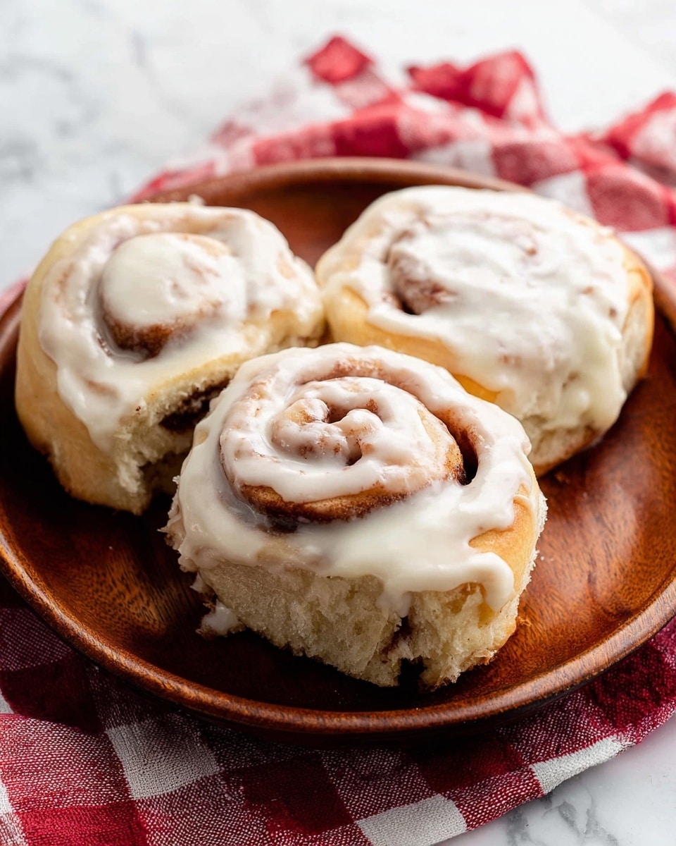 The image shows a side-by-side of a black muffin pan holding nine cinnamon rolls each, placed on a white marbled surface. On the left side, the cinnamon rolls are raw dough, light beige in color with darker brown cinnamon swirls visible in two to three of each roll's spirals. Each roll sits in its individual circular cup with a slightly rough and doughy texture. On the right side, the cinnamon rolls are baked, golden brown with deep caramelized cinnamon swirls that make the spiral pattern clear and rich in color and texture. The rolls look soft with a slightly crispy top and are still set in the same black muffin pan on the white marble. photo taken with an iphone --ar 4:5 --v 7