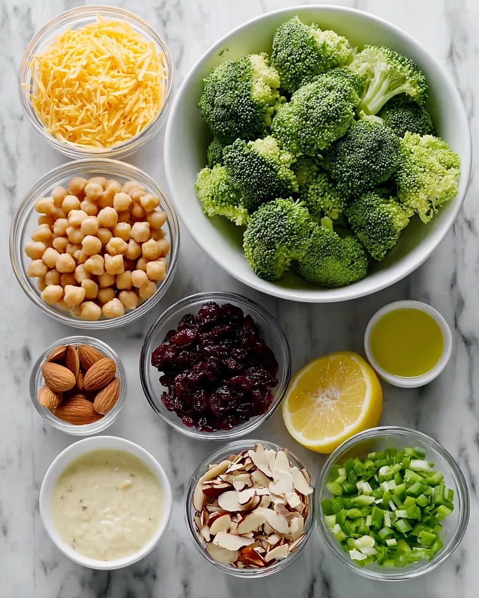 The image shows ingredients for a fresh broccoli salad arranged on a white marbled surface. There is one large white bowl filled with bright green broccoli florets with a rough, bumpy texture forming the main layer. Around it are several small glass and white bowls holding different ingredients: shredded orange cheddar cheese, pale yellow chickpeas, chopped green onions, dark red dried cranberries, chopped almonds with light and dark brown skin, a lemon half showing its juicy yellow interior, a small white bowl with a pale creamy dressing, and another small white bowl with clear golden olive oil. All ingredients are neatly placed, creating a colorful and vibrant display. Photo taken with an iphone --ar 4:5 --v 7