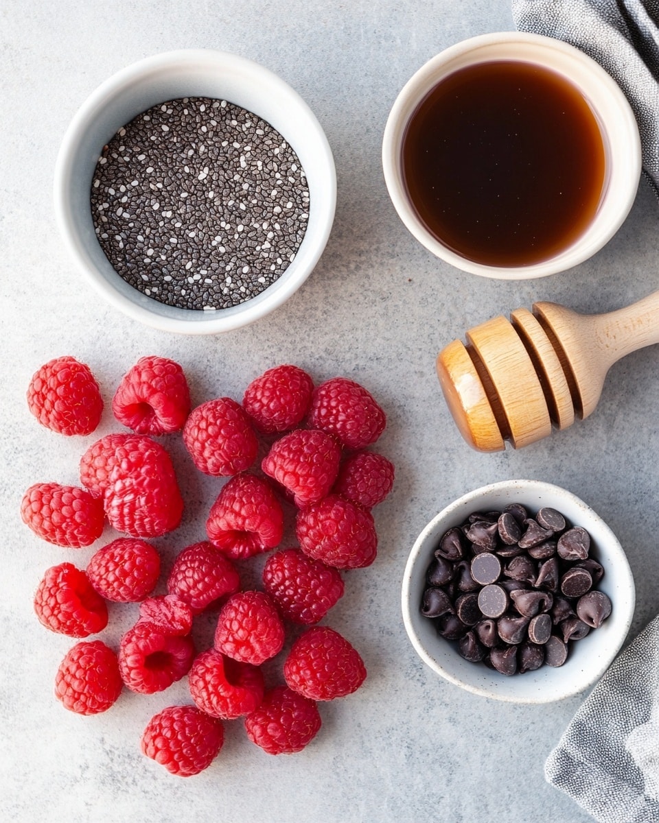 A white oval plate is filled with six round chocolate-covered treats with a smooth, slightly glossy dark brown surface. One of the treats is cut in half, showing a bright red raspberry filling with a juicy texture inside. Around the chocolate pieces, fresh whole raspberries are scattered, adding a vibrant red color contrast. The plate is placed on a white marbled textured surface. In the background, a small white bowl with more raspberries is partially visible. Photo taken with an iphone --ar 4:5 --v 7